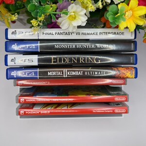 Puede incluir: Una pila de cajas de juegos de video, incluyendo Final Fantasy VII Remake Intergrade, Monster Hunter: World, Elden Ring, Mortal Kombat Ultimate, Luigi's Mansion 3, Animal Crossing: New Horizons y Pokemon Shield.