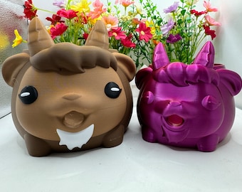 May include: Two ceramic animal planter pots. The first pot is brown and shaped like a goat with white horns. The second pot is a bright pink and shaped like a unicorn with a white horn.