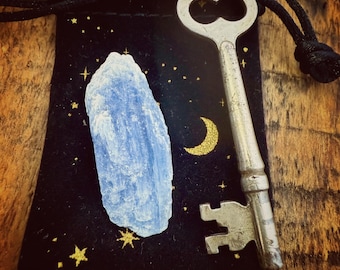 Llave antigua con hoja de cianita azul – Amuleto de oportunidad y protección, en bolsa de terciopelo negro con luna creciente y estrellas, talismán.