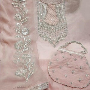 Puede incluir: Un vestido rosa bordado con adornos plateados y un bolso a juego bordado en rosa.