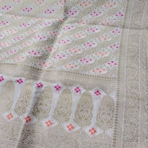 May include: White fabric with a silver paisley pattern and small pink and orange dots. The fabric has a border with a more intricate silver pattern.