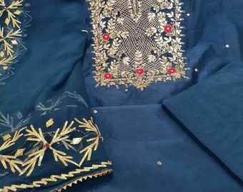 May include: A dark blue embroidered dress with gold and red embellishments. The dress has a long sleeve and a high neckline. The fabric is a soft, flowing material.