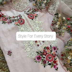May include: A pink sheer fabric with delicate floral embroidery. The embroidery features white, pink, and green flowers. The fabric has a scalloped edge and the text "Style For Every Story" is printed on the fabric.