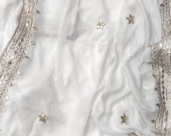 May include: White sheer fabric shawl with a gold embroidered border featuring mirrored stars and geometric patterns.