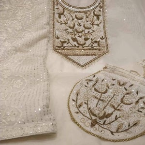 May include: A white embroidered dress with a matching clutch bag. The dress and bag feature intricate floral designs with gold and white beads.
