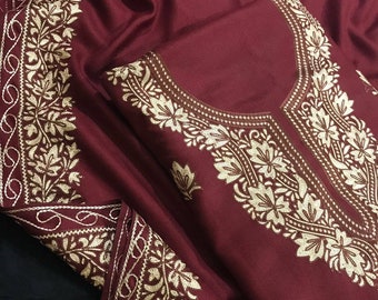 May include: A maroon shawl with intricate gold embroidery. The shawl features a floral pattern and a scalloped edge.