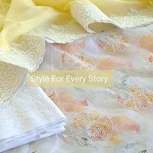 May include: A white sheer fabric with a yellow sheer fabric overlay. The white fabric has a floral pattern and the yellow fabric has a white lace trim. The text "Style For Every Story" is printed on the fabric.
