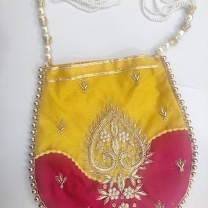 May include: A small, yellow and red fabric purse with gold embroidery and pearl accents. The purse has a white pearl and gold chain strap.