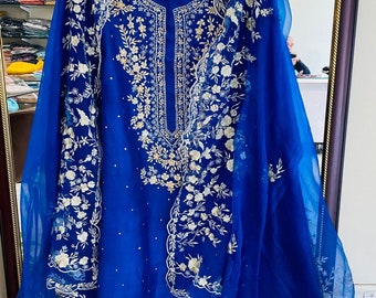 May include: A royal blue embroidered dress with a matching dupatta. The dress features intricate floral designs in silver thread. The dupatta is sheer and has a similar floral pattern.