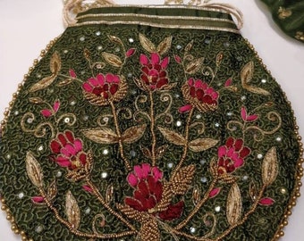 以下が含まれることがあります： オリーブグリーンのビーズ刺繍ハンドバッグ。ピンクの花、金の刺繍、ビーズのハンドルが特徴です。縁は金のビーズでトリミングされ、バッグには真珠のようなストラップが付いています。