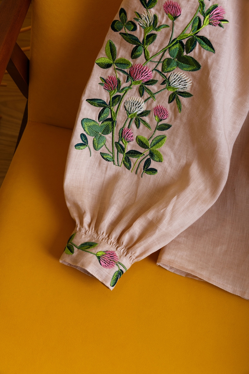 May include: A pale pink linen blouse with embroidered clover flowers in shades of green and pink.