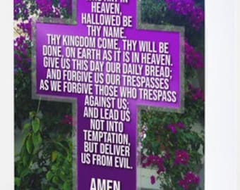 May include: Purple cross with the Lord's Prayer printed on it. The cross is surrounded by purple flowers.