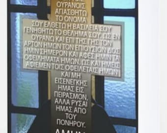 May include: A stained glass window with a cross and the Lord's Prayer in Greek text. The text reads: "Our Father, who art in heaven, hallowed be thy name. Thy kingdom come, thy will be done, on earth as it is in heaven. Give us this day our daily bread. And forgive us our debts, as we also have forgiven our debtors. And lead us not into temptation, but deliver us from evil. Amen."