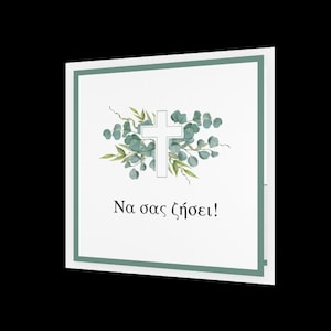 May include: Square white card with a light green border. The card features a white cross surrounded by green leaves and a floral design. The Greek text "Na sas zesei!" is printed below the cross.