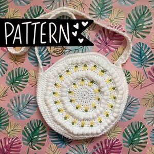 May include: White crocheted bag with a yellow floral pattern. The bag has a long strap and is ideal for carrying everyday essentials.