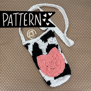 May include: A crocheted cow-print bottle holder with a pink crocheted patch on the front. The holder has a long strap for carrying.