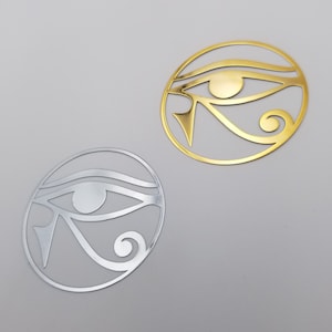 Puede incluir: Dos amuletos de metal en forma de Ojo de Horus, uno dorado y otro plateado.