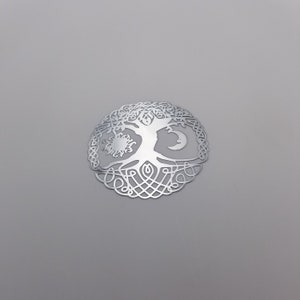 May include: A silver metal tree of life pendant with a sun and moon design. The tree is surrounded by intricate knotwork.