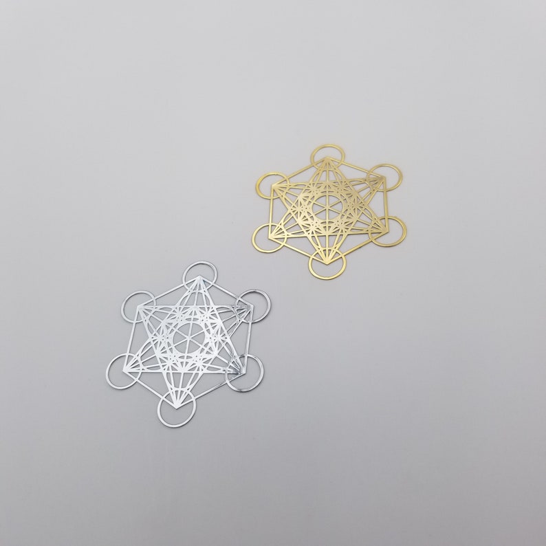 May include: Two geometric metal shapes, one gold and one silver, with intricate designs. The shapes are similar and resemble a star of David.