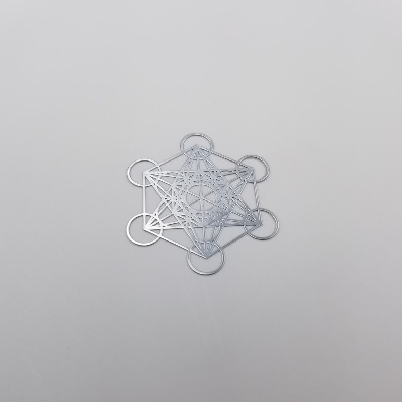 May include: A silver metal geometric design with a star shape in the center. The design is made up of overlapping circles and lines.