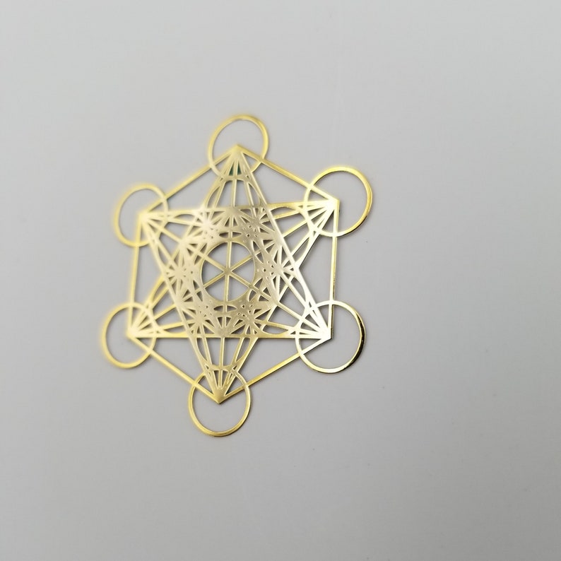 May include: A gold metal geometric design with a intricate pattern. The design is a six-pointed star with a circle in the center.