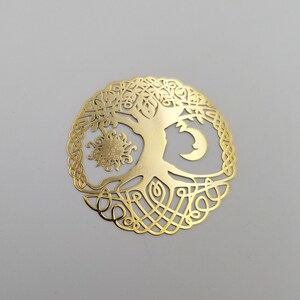 May include: Gold-toned metal tree of life pendant with a sun and moon design. The tree has intricate branches and roots.