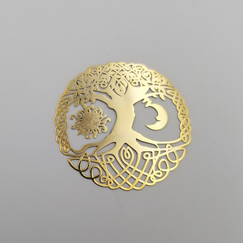 May include: Gold-toned metal tree of life pendant with a sun and moon design. The tree has intricate branches and roots.