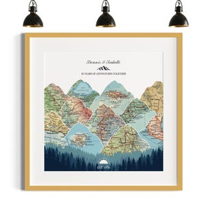 May include: Framed art print featuring a mountain range design composed of vintage map sections. The print includes the text "Dennis & Isabelle" and "50 Years of Adventures Together." A forest silhouette and the text "EST 1976" are at the bottom.