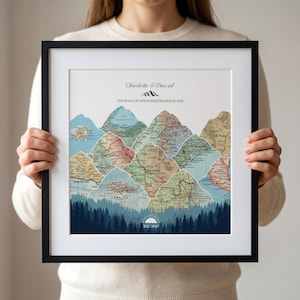 May include: A framed wall art print featuring a mountain range composed of vintage map segments. The text reads Charlotte & David, The Road of Life is Sweeter Side by Side, and EST 2010. A dark blue forest silhouette sits at the base with a sun icon.