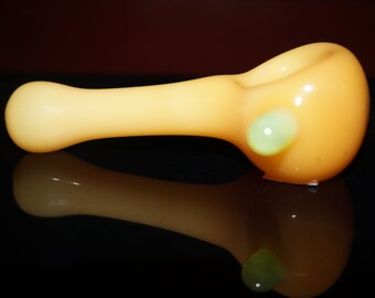 May include: A yellow glass pipe with a green glass accent. The pipe is on a black surface.