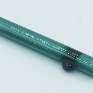 May include: A teal glass pipe with a black glass marble at the end.