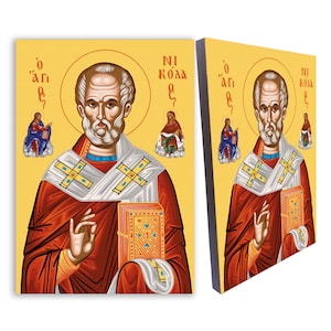 Puede incluir: Un icono religioso que representa a San Nicolás, un hombre barbudo con ropas rojas que sostiene un libro. El icono tiene un fondo amarillo con texto griego que dice "O Agios" y "Ni Kolla O".