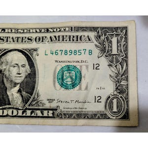 May include: A United States one-dollar bill featuring a portrait of George Washington on the left, the text Federal Reserve Note, the green Department of the Treasury seal, the series year 2017, and the signature of Steven T. Mnuchin.