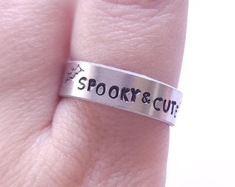 May include: A silver ring with the words "Spooky & Cute" engraved on it.