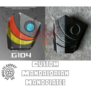 May include: A 3D printed Mandalorian handplate with a black and gray color scheme. The handplate has a circular design with a raised center and a textured surface. The text "G104" is printed on the bottom of the handplate. The image also includes the text "CUSTOM MANDALORIAN HANDPLATES".