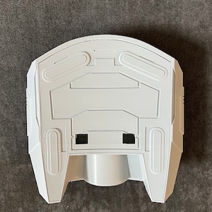 K&ouml;nnte beinhalten: Wei&szlig;es Plastikmodell eines Raumschiffs mit abgerundeter Oberseite und spitzem Boden. Das Modell hat ein detailliertes Design mit verschiedenen Linien und Rillen.