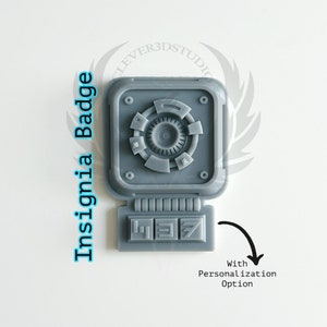 May include: Gray plastic insignia badge with a circular design and a rectangular panel with the numbers 1, 3, and 7. The badge has a personalization option.