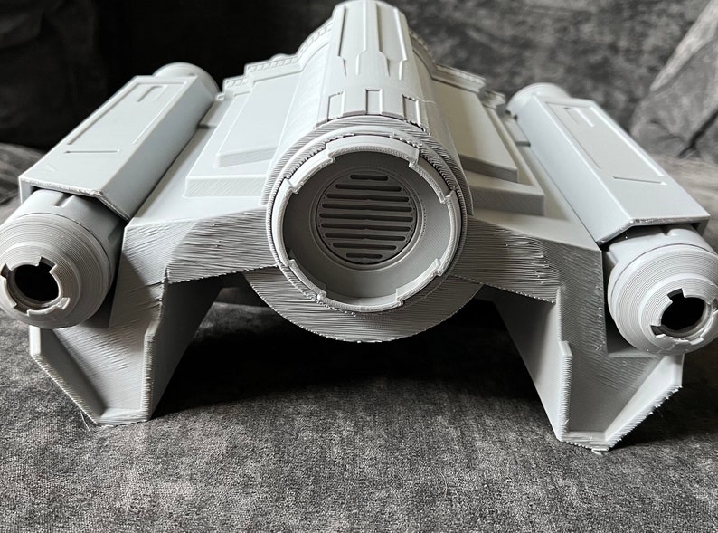 K&ouml;nnte beinhalten: Ein graues 3D-gedrucktes Modell eines Raumschiffs mit zwei Triebwerken an jeder Seite und einer gro&szlig;en runden L&uuml;ftungs&ouml;ffnung in der Mitte.