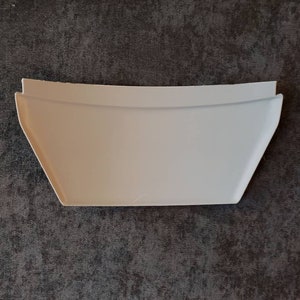 Puede incluir: Un revestimiento de estante de pl&aacute;stico blanco con un borde curvo. El revestimiento est&aacute; dise&ntilde;ado para encajar en una esquina y evitar que los art&iacute;culos se deslicen.