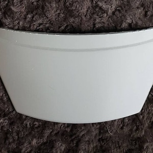 Puede incluir: Pieza curva de pl&aacute;stico blanco con una superficie lisa. Esta pieza probablemente forma parte de un objeto m&aacute;s grande.