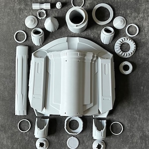 K&ouml;nnte beinhalten: Ein Satz aus 3D-gedruckten Kunststoffteilen f&uuml;r ein Raumschiffmodell. Die Teile sind grau und umfassen einen Hauptk&ouml;rper, Fl&uuml;gel und Motorteile.