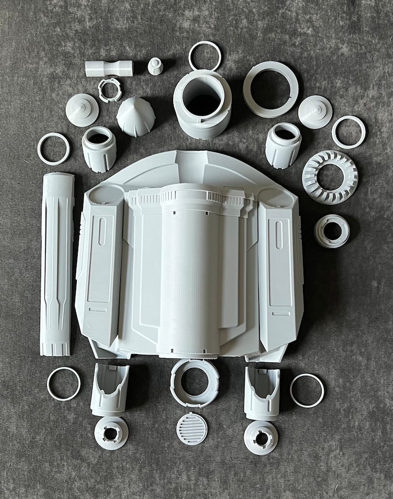 K&ouml;nnte beinhalten: Ein Satz aus 3D-gedruckten Kunststoffteilen f&uuml;r ein Raumschiffmodell. Die Teile sind grau und umfassen einen Hauptk&ouml;rper, Fl&uuml;gel und Motorteile.