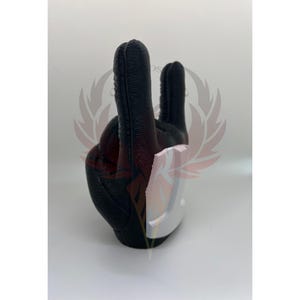 May include: A black rubber hand sculpture making the rock and roll hand gesture. The hand is textured and has a white base.