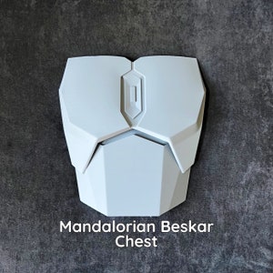 May include: White plastic Mandalorian Beskar Chest armor prop. The chest plate has a raised, rectangular design with a central, diamond-shaped panel.