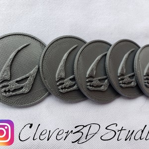 May include: Five gray 3D printed round tokens with a raised design of a stylized horn. The tokens are arranged in a row.