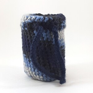 Puede incluir: Una maceta de ganchillo con un patrón de rayas azules, grises y blancas. La maceta está hecha con un hilo grueso y tiene un tejido suelto y texturizado.
