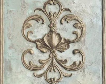 May include: Ornate, gold-colored relief design on a textured, pale blue and gray background. The central motif is a stylized floral element, surrounded by scrolling flourishes and framed by a decorative border. The design evokes a sense of classic elegance.