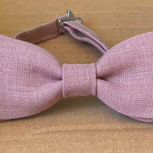 May include: A dusty rose linen bow tie with an adjustable strap and silver buckle.