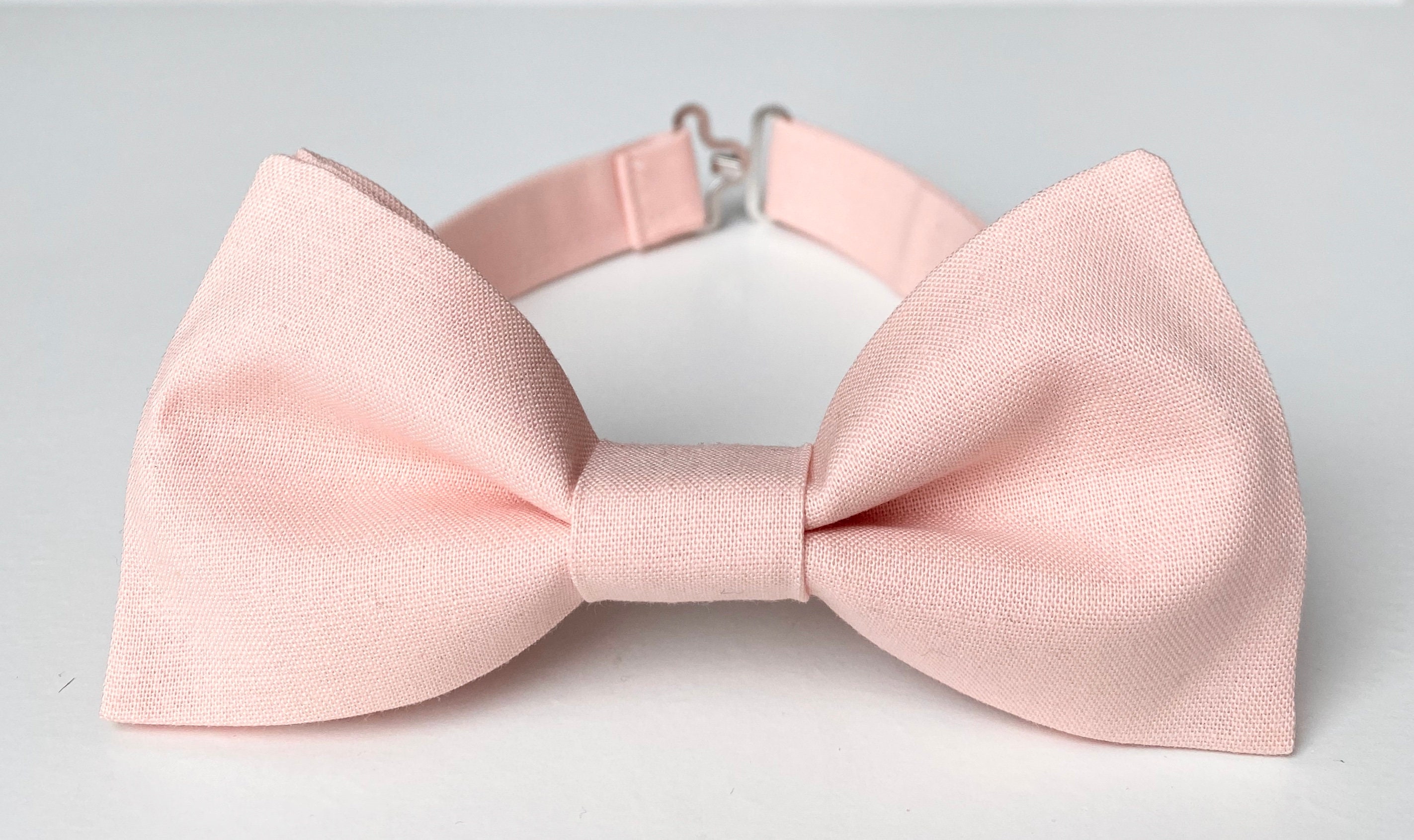 A blush pink bow tie with white dots