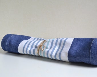 May include: A rolled up blue and white striped kitchen towel tied with brown twine.